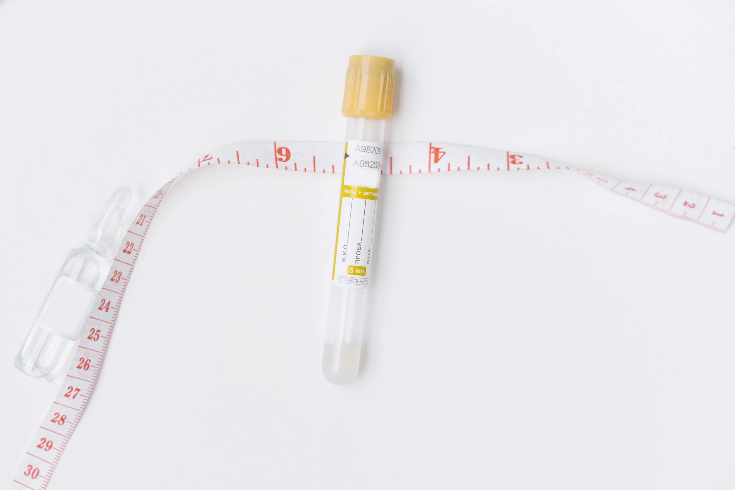 Image of an empty test tube and a measuring tape on a white background, ideal for healthcare and laboratory themes.